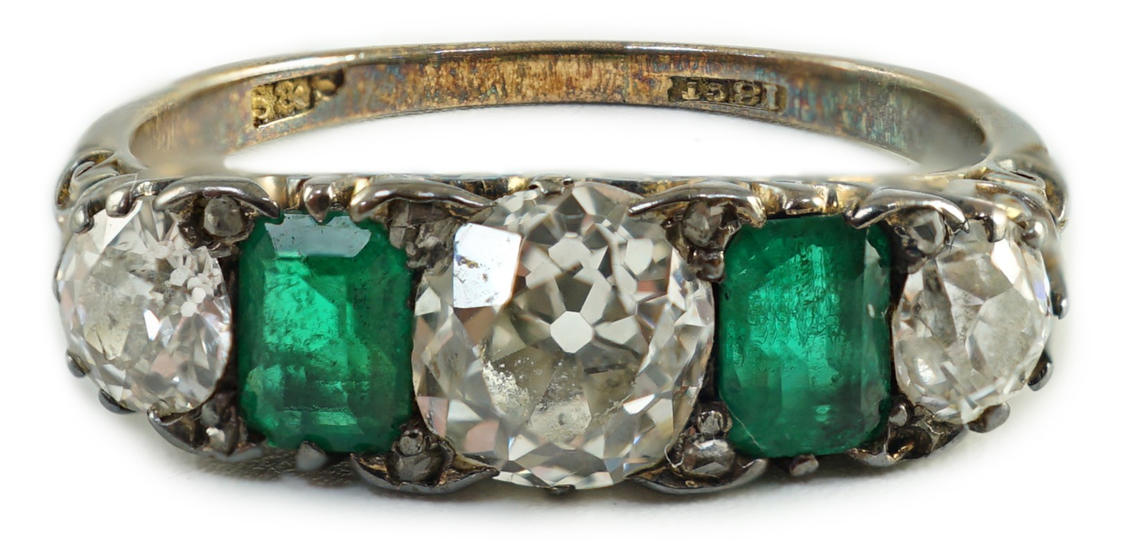 An early 20th century 18ct gold, three stone diamond and two stone emerald set half hoop ring